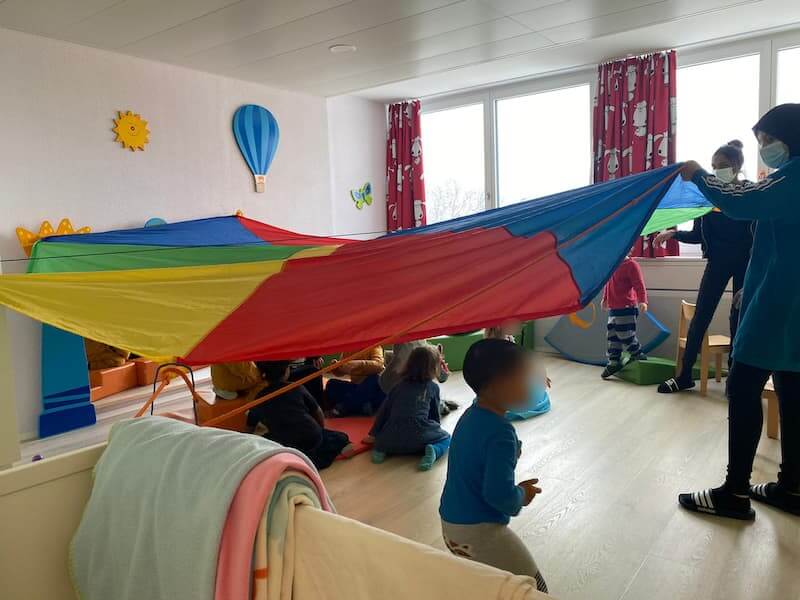 wir spielen mit dem regenbogentuch kinderkrippe und waldkinderkrippe blueemli in zuerich witikon